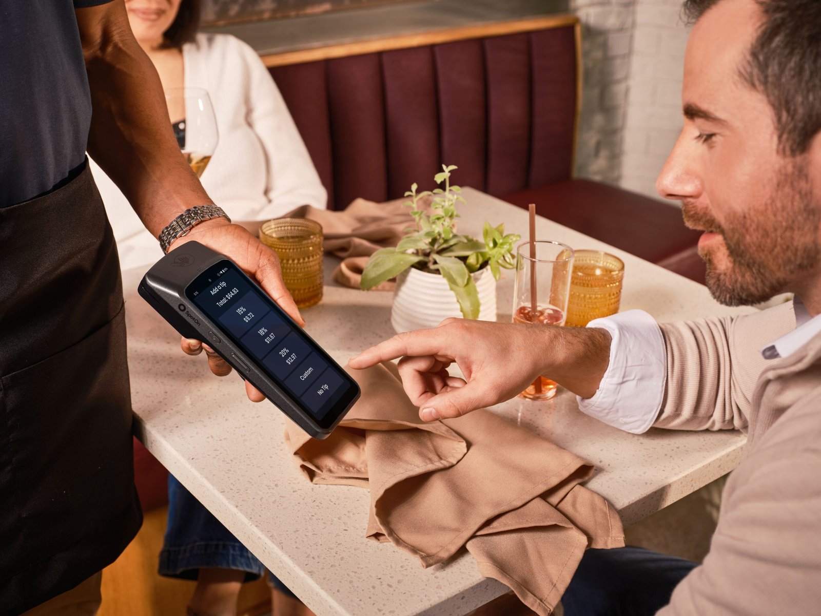 Cliente en restaurante usando sistema POS para registrar propina digital en el cierre del turno.